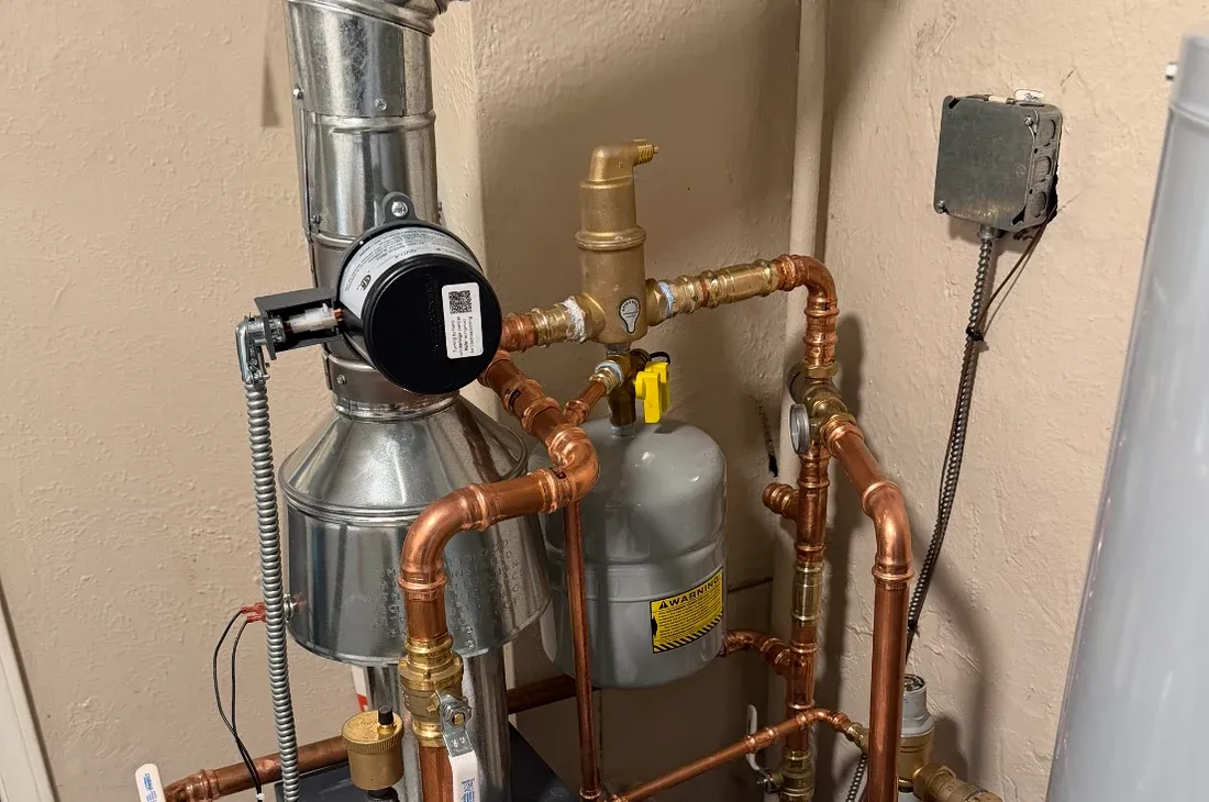 Copper boiler piping, brass fittings, gray expansion tank, and galvanized flue photographed on an OnCape job.