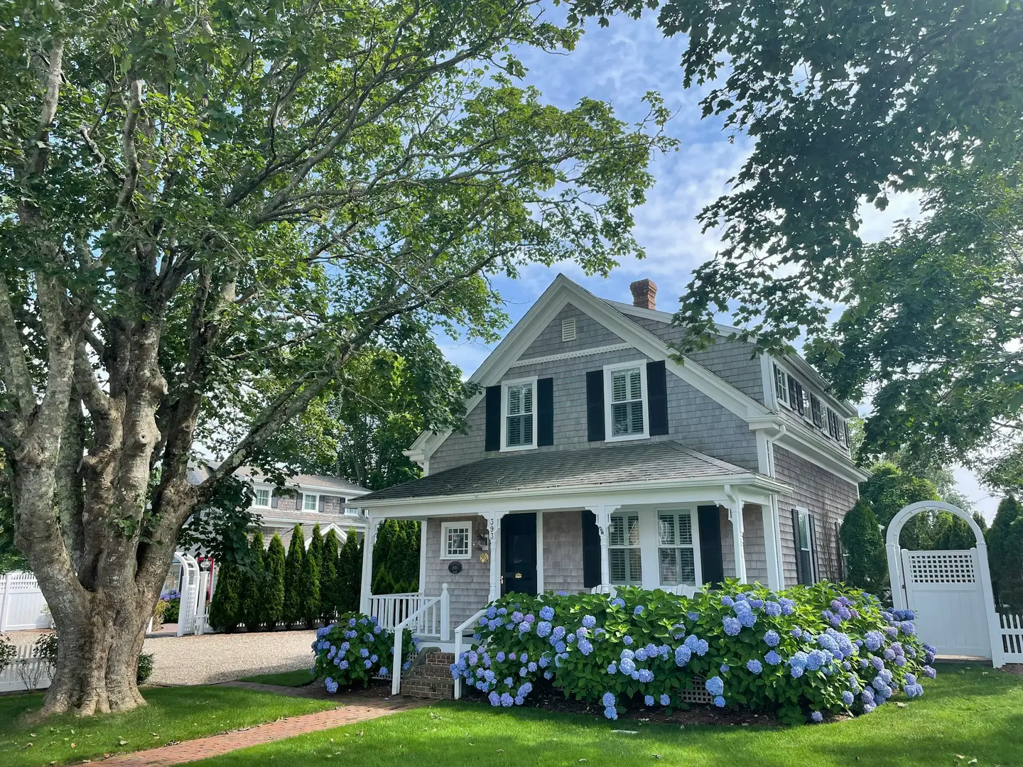 Shingled Cape Cod home with a welcoming porch and blue hydrangeas in Chatham