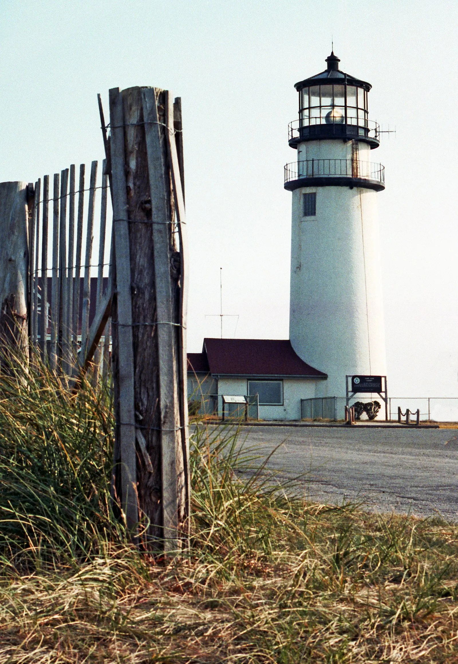 Highland Lighthouse beside a weathered fence in Truro, Cape Cod
